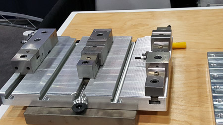 A serrated, slotted pallet, loaded with various mini vises